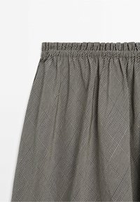 Jupe avec taille élastique et motif à carreaux noir et blanc formant de grandes formes losanges sur le tissu.
