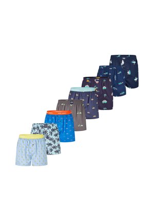 Syv par farverige herreboxershorts med forskellige mønstre, herunder citroner, palmer, cykler, scootere, biler og surfbrætter, arrangeret i en diagonal linje.