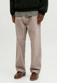 Jasnoszare, szerokie spodnie wykonane z trwałego materiału, o prostym kroju i widocznym szyciu, w połączeniu z brązowymi półbutami.