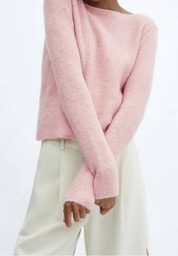 Pull en maille côtelée rose à manches longues, fabriqué en matériau tricot doux. Assorti à un pantalon ample de couleur claire.