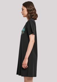 Schwarzes T-Shirt-Kleid mit kurzen Ärmeln, lockerer Passform und abgerundetem Saum. Mit Grafikdesign in Türkis und Braun auf der Vorderseite.