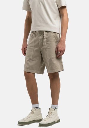 Pantalones cortos cargo beige con un ajuste relajado, que cuentan con bolsillos frontales y una cintura con cordón, fabricados con un material de algodón duradero.