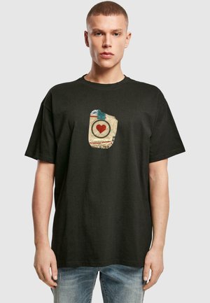 Čierne bavlnené tričko s centrálnou grafikou béžového „patu“ s červeným srdcom vo vnútri kruhu. Krátke rukávy a voľný strih.