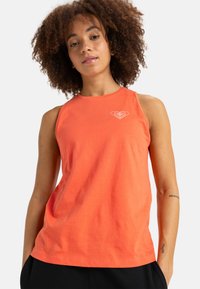Mouwloos oranje tanktop van katoen; heeft een ronde halslijn en een klein wit logo op de linkerkant van de borst. Gladde textuur.