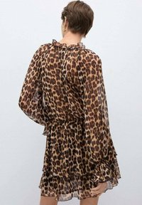 Haljina s leopard uzorkom, s višeslojnim volanima, dugim prozirnim rukavima, suženim strukom i volanastim izrezom. Napravljena od laganog materijala.