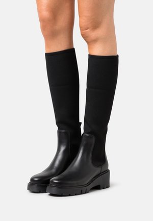 Czarne skórzane botki za kostkę z grubą podeszwą i elastyczną czarną cholewką, charakteryzujące się eleganckim designem i minimalnym zdobieniem.