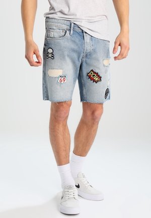 Jasnoniebieskie szorty jeansowe z przetarciami i różnymi naszywkami, w tym czaszką, "Route 69" oraz komiksowymi akcentami "Pow!".