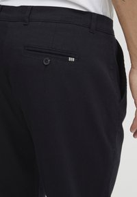 Marineblå bukser med strukturert stoff, med en sidelomme med knapp og en stripete detalj. Slim fit med et rent design.