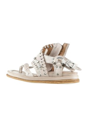 Sandalo in pelle bianca con molteplici cinturini decorati con borchie e una fibbia, suola piatta con finitura in legno chiaro.