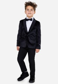 Traje de terciopelo negro con un chaleco de satén, camisa de vestir blanca y pajarita negra; combinado con pantalones negros y zapatillas.