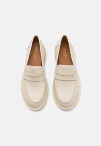 Mocassini beige con tomaia in pelle textured, dettagli cuciti e suola in gomma di colore chiaro. Presentano un delicato marchio sulla soletta.