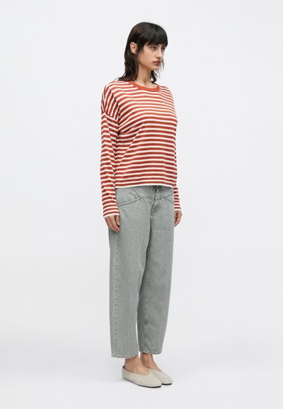 Κόκκινο και λευκό ριγέ πουκάμισο με μακριά μανίκια, ανοιχτόγριες τζιν ψηλόμεσες παντελόνες και μπεζ παπούτσια slip-on. Απλός σχεδιασμός, άνετη εφαρμογή και μαλακή υφή.