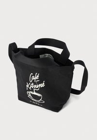 Svart kanvas tote bag med stoffhåndtak, med et hvitt trykket design av en kaffekopp og teksten "Café Kitsuné Paris".