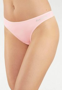 Lichtroze bikini slips van zacht stof. Beschikt over een eenvoudig ontwerp met een naadloze afwerking en het woord "FLASHLIGHTS" in lichtgrijs.