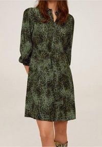 Robe boutonnée verte à motif serpent, avec des manches trois-quarts, texture lisse, design semi-ajusté et col classique.