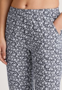 Bloemenprintbroek met een marineblauwe basis en witte bloemen, elastische tailleband, zijzakken en een relaxte pasvorm.