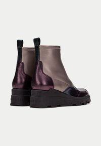 Botas de tobillo que combinan cuero taupe liso y cuero burdeos texturizado, con una suela de goma negra gruesa y una tira para facilitar su puesta.