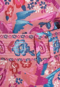 Tela con estampado floral en tonos de rosa, azul y púrpura, con un cinturón ancho que cuenta con una hebilla rectangular y costuras decorativas.
