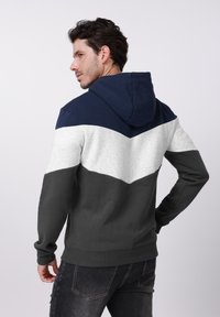 Hanorac cu glugă, cu design în nuanțe de bleumarin, gri și alb, confecționat din material texturat. Buzunar tip cangur și manșete striate la tiv.