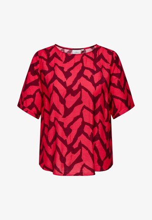 Rdeča bluzica s kratkimi rokavi z drzno cik-cak vzorcem v temnejši rdeči barvi, ki ima okroglo neckline in ohlapen kroj. Lahka tkanina.