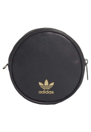 Pyöreä musta Adidas-laukku, jossa kultainen logo ja vetoketjusuljin reunan ympärillä.
