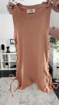 Różowa, żeberkowana koszulka bez rękawów z detalami w postaci sznurowania po bokach. Posiada okrągły dekolt. Materiał ma miękką teksturę.
