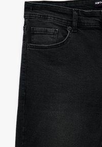 Jeans negros de corte slim-fit con un diseño clásico de cinco bolsillos, elaborados en denim con una textura suave y detalles de costura sutiles.