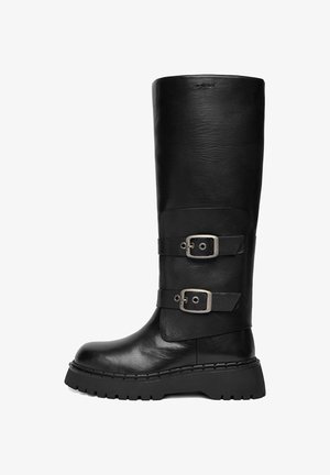 Czarny skórzany kozak za kolano z masywną podeszwą i dwoma srebrnymi paskami z klamrami po boku, pokazany z profilu na białym tle.