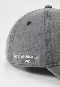 Gray cotton cap with a structured design. Features black eyelet for ventilation and white embroidered text "ARKK COPENHAGEN ESL 2015."
