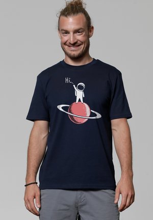 Marineblaues Baumwoll-T-Shirt mit kurzen Ärmeln, mit einer Grafik einer Figur in einem Raumanzug, die auf einem roten Planeten mit Ringen steht, und dem Text "Hallo...".