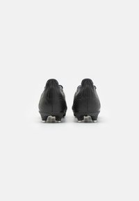 Scarpe da calcio nere con un design elegante, realizzate in materiale sintetico liscio, e con tacchetti posizionati strategicamente per una migliore trazione. Vista posteriore che evidenzia i contorni.