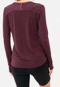 Maglietta sportiva a manica lunga di colore bordeaux con una texture liscia, caratterizzata da un accento giallo sulla scollatura posteriore e un design aderente.