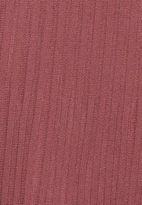 Gros plan sur un tissu tricoté rose avec un motif en côtes verticales texturé.