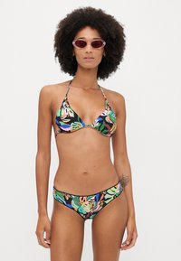 Triangular bikini in black with multicolored tropical leaf patterns. Material appears smooth with adjustable straps on the top.