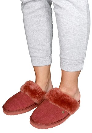 Rode suedine slippers met een luxe, donzige bontkraag. Rond gevormd, met een rubberen zool, voorzien van een klein rond accentdetail. Draagt bij grijze cropped broeken.