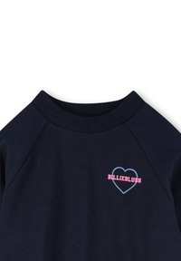 Laivastonsininen collegepaita, jossa on ribattu pyöreä kaula-aukko. Sisältää pinkin ja sinisen sydänlogon, jossa on teksti "BILLIEBLUSH". Pehmeää puuvillasekoitemateriaalia.