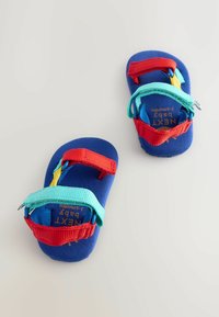 Blå babysandaler med röda, turkosa och gula remmar. Mjukt material med två justerbara remmar för säker passform och komfort.