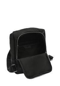 Zaino in tessuto nero con chiusura a zip, dotato di una tasca interna e un design elegante. Le cinghie sono regolabili con accessori in metallo.