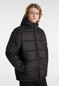 Chaqueta acolchada negra con cremallera frontal, capucha y diseño acolchado. Cuenta con puños elásticos y un logo en el pecho, ofreciendo aislamiento y calidez.