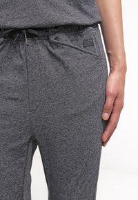 Mörkgrå träningsbyxor med elastisk midja och snörning. Har sidofickor och en liten logotag. Texturerad tyg för komfort.