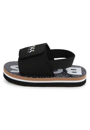 Sort børnesandal med justerbar frontrem, elastisk hælrem og mønstret sål med hvide og brune mellemlag.