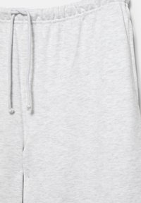 Világosszürke melegítőnadrág elasztikus derékpánttal és fehér húzózsinórral, amely megmutatja a szövet textúráját és a varrás részleteit.