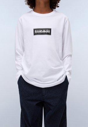 Wit t-shirt met lange mouwen en een zwart rechthoekig ontwerp met de tekst "NAPAPIJRI geographic" in het midden. Zachte katoenen stof, losse pasvorm.