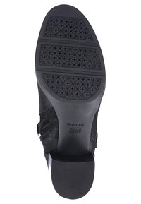Stivaletto alla caviglia in suede nero con suola in gomma testurizzata a perforazioni circolari, zip laterale e branding discreto sulla suola.