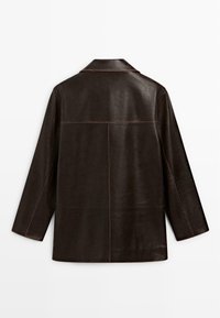 Bruine leren jas met een losse pasvorm, geknopt kraag en zichtbare stiksels; gladde textuur met een licht glanzende afwerking.