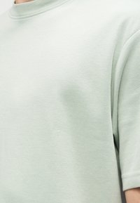 Μέντα πράσινο κοντομάνικο μπλουζάκι με στρογγυλή λαιμόκοψη, κατασκευασμένο από απαλό βαμβακερό υλικό, με λεία υφή και ελάχιστες ραφές.