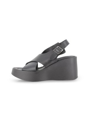 Sandalia cuña negra hecha de cuero suave, con un diseño de tiras cruzadas, hebilla ajustable y una suela de plataforma gruesa.