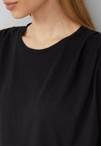 Zwarte t-shirt van zachte katoen met een ronde halslijn en korte mouwen, met een gladde, effen textuur zonder patronen.