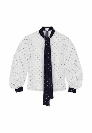 Blouse blanche à manches longues avec petits pois noirs, manches bouffantes, poignets noirs et une longue cravate noire à pois.
