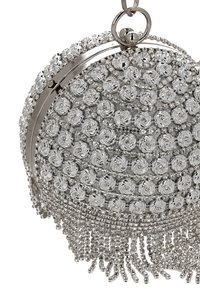 Kulatá stříbrná kabelka s propracovanými spirálovými vzory, kovovými akcenty a třásňovým detailem ve spodní části. Vyrobená z texturovaných materiálů.